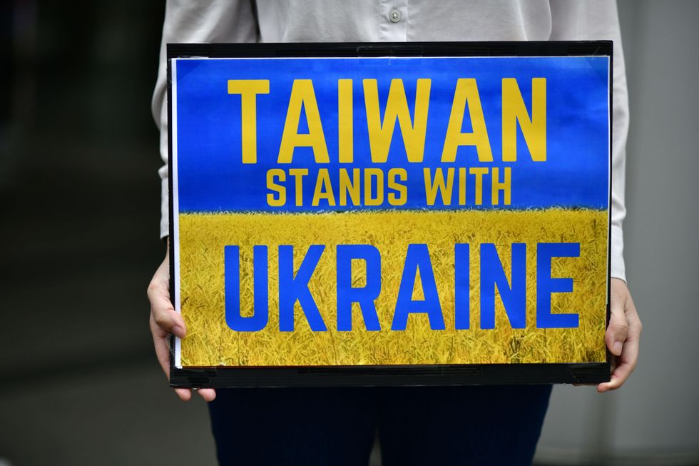 A protester holds a sign saying "Taiwan stands with Ukraine"
