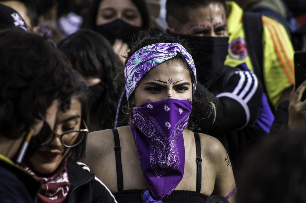A protester with a purple scarf, a color used to demonstrate gender equality in Colombia.