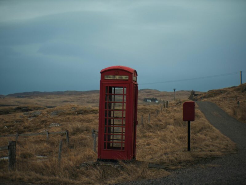 A red phone booth alongside the road