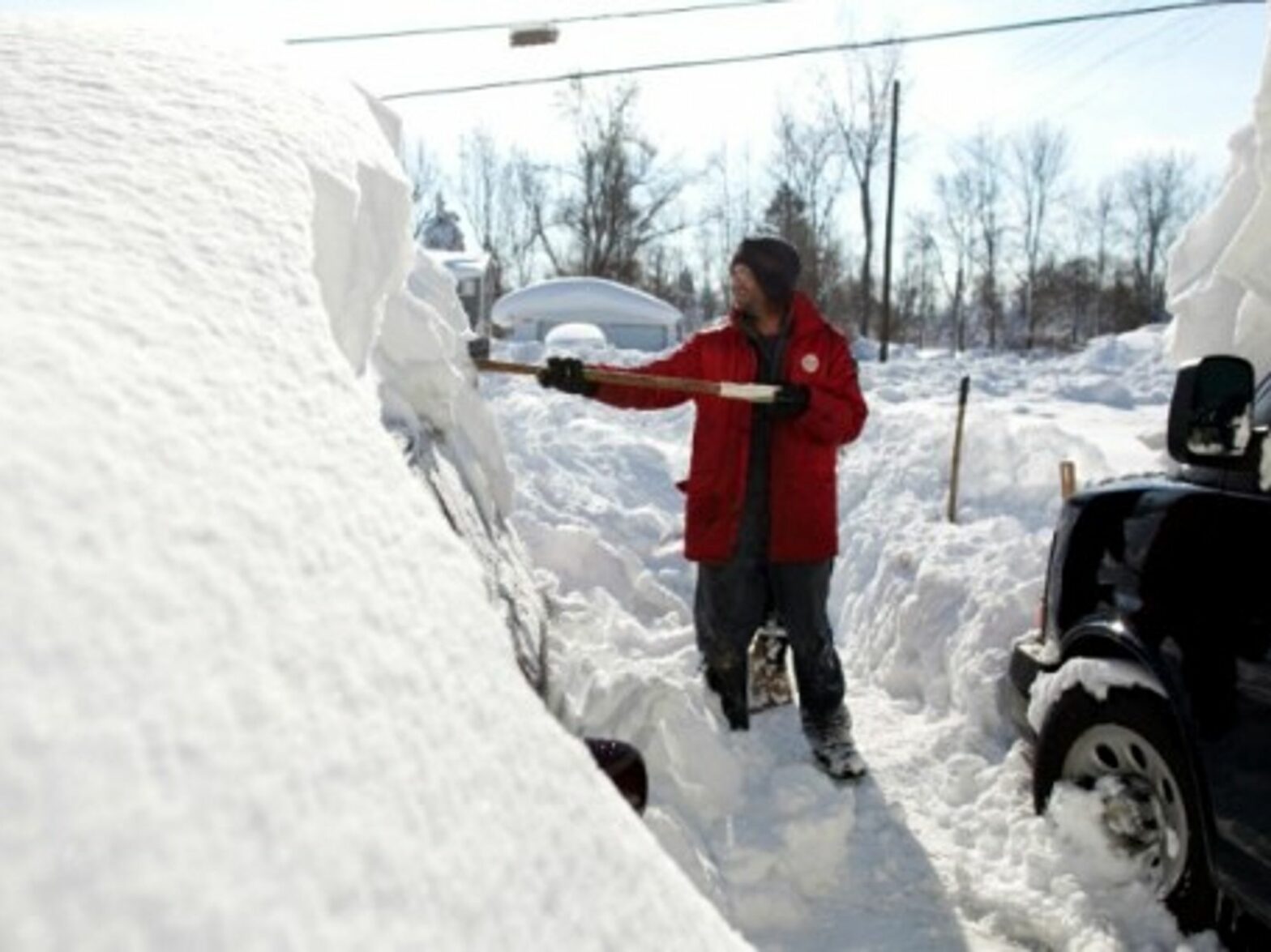 A resident of Alden, New York, shovels snow from atop his car.