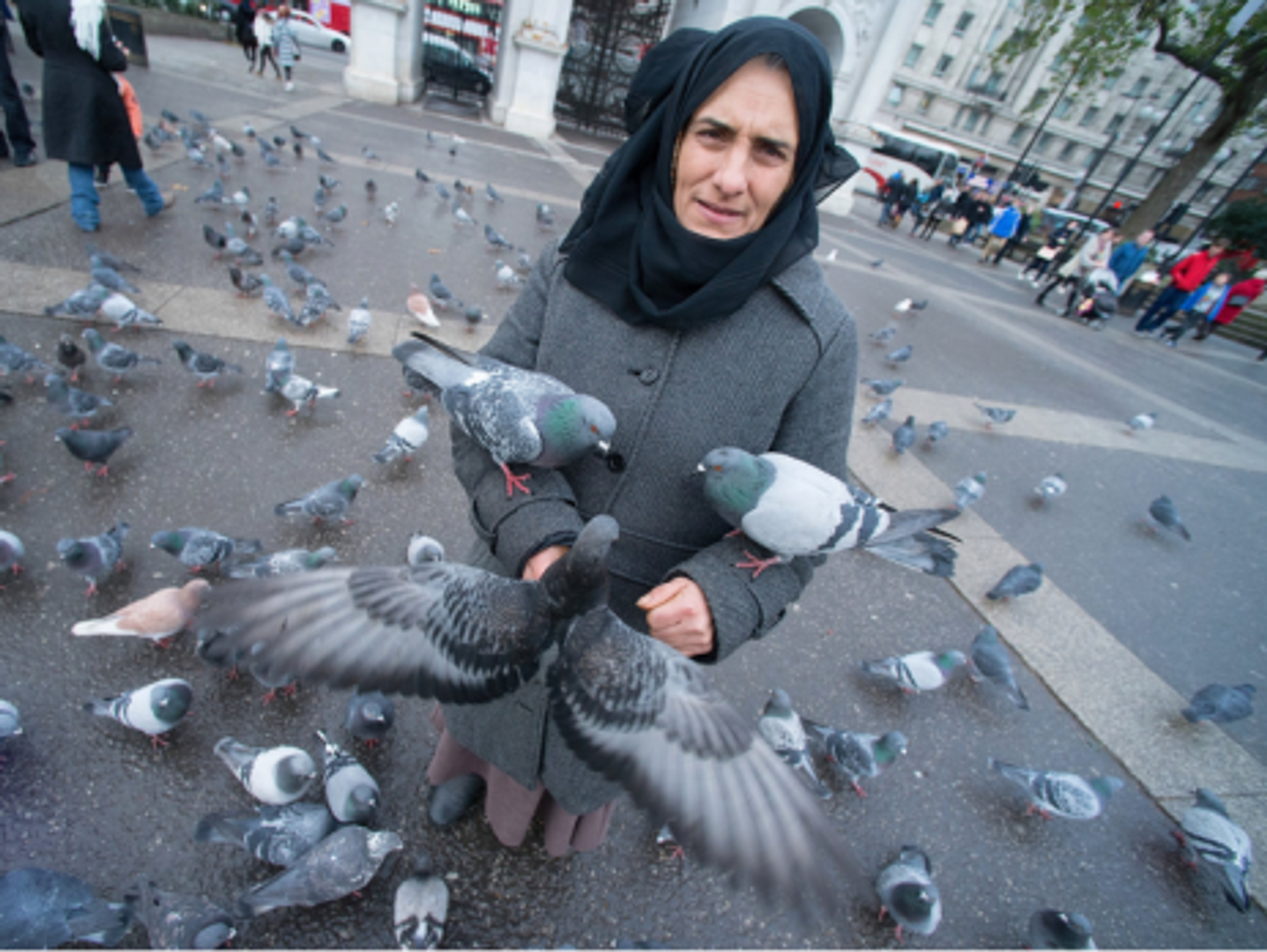 A Romanian woman feeding pigeons at Marble Arch in London.