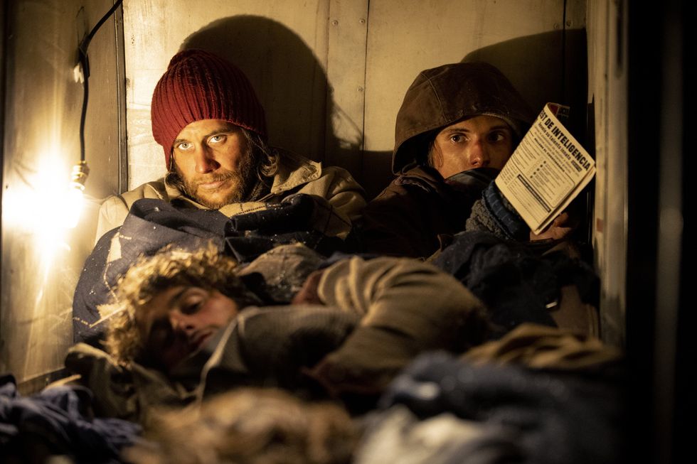 A scene from ​Society of the Snow ​of members of the rugby team huddled together for warmth