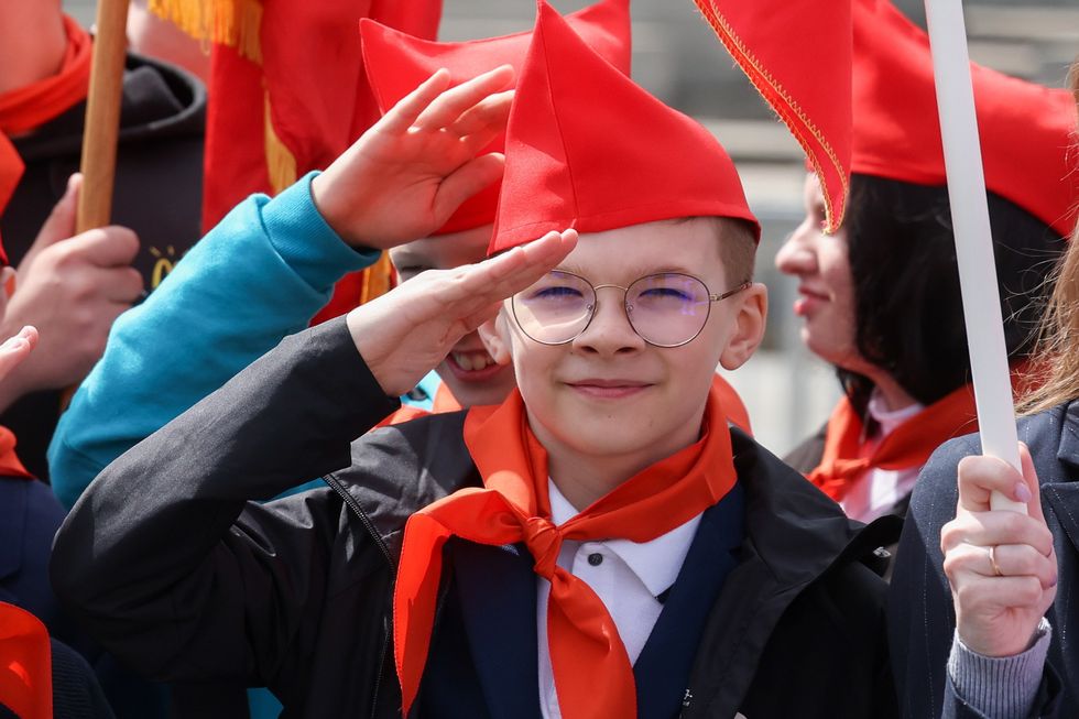 A school boy salutes at a pioneer induction ceremony in Red Square, Moscow on May 21, 2023.