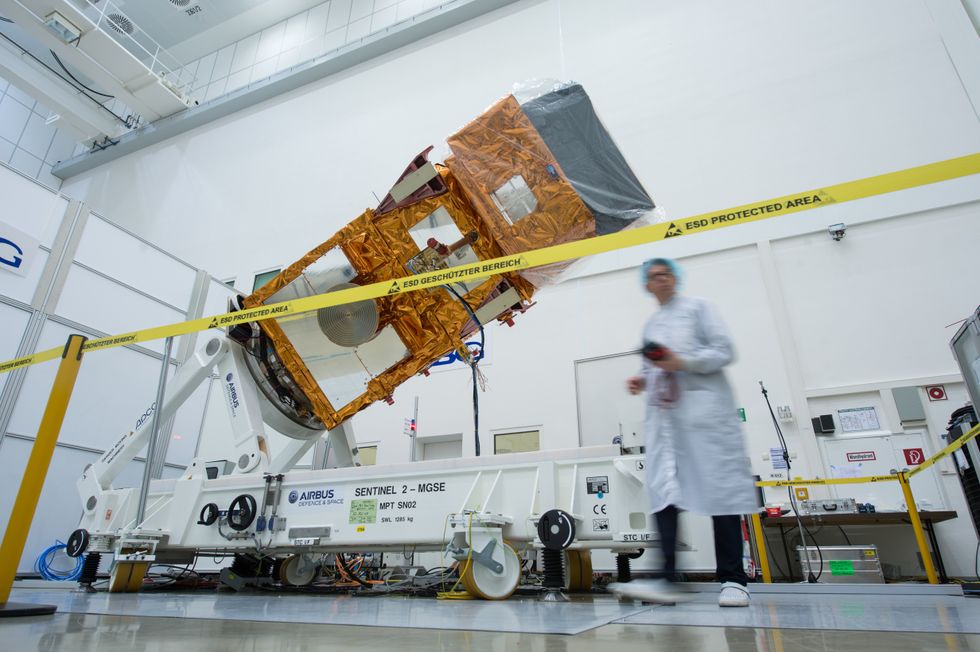 A scientist in a white lab working on Sentinel-2A wrapped in gold film