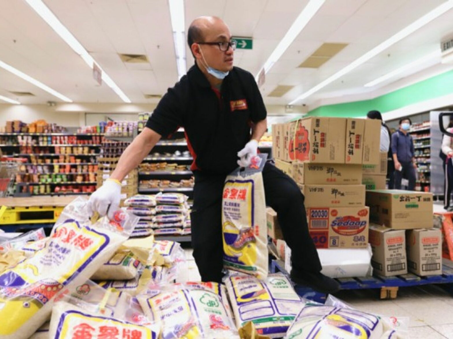 A shop assistant in Hong Kong, China, moves freshly supplied rice in a supermarket.