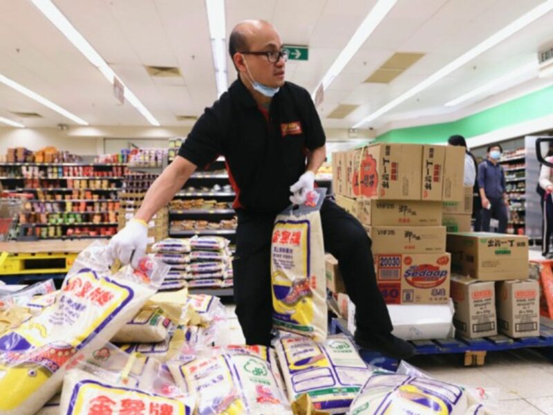 A shop assistant in Hong Kong, China, moves freshly supplied rice in a supermarket.
