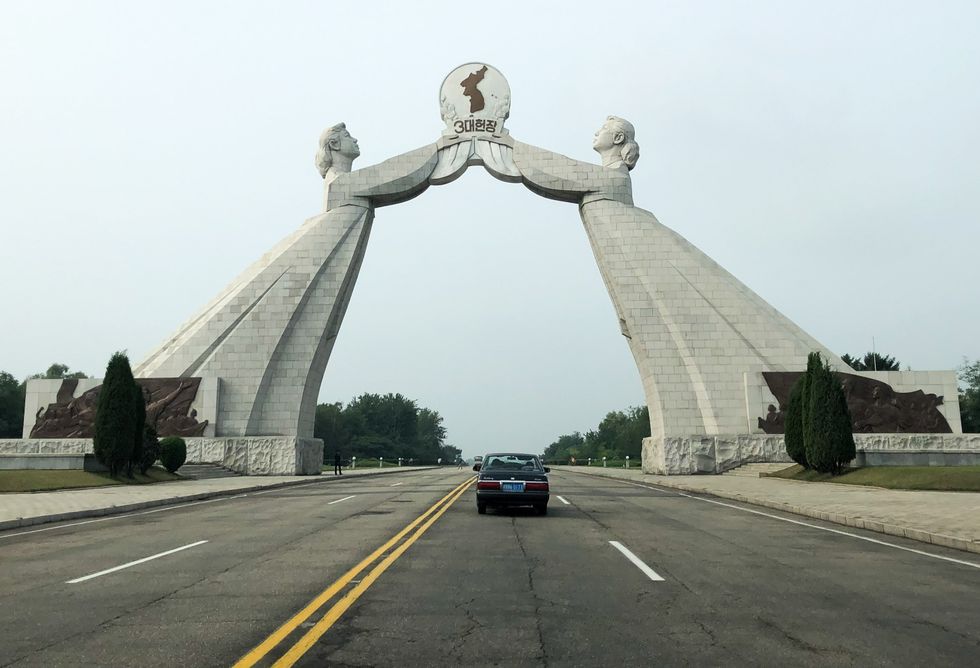 A single car driving under the Arch of Reunification