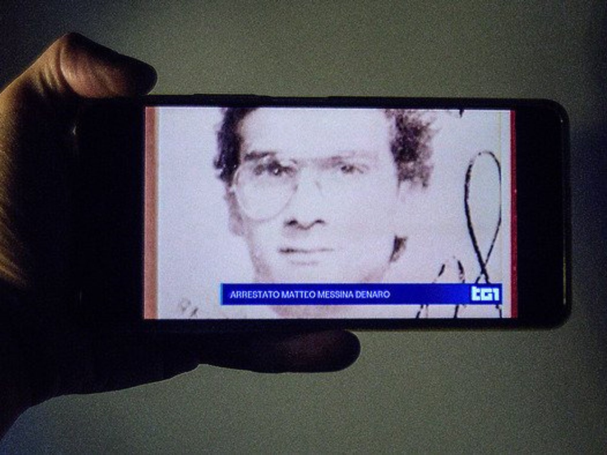 A smartphone screen with live news from an Italian television channel about the arrest of fugitive Matteo Messina Denaro.