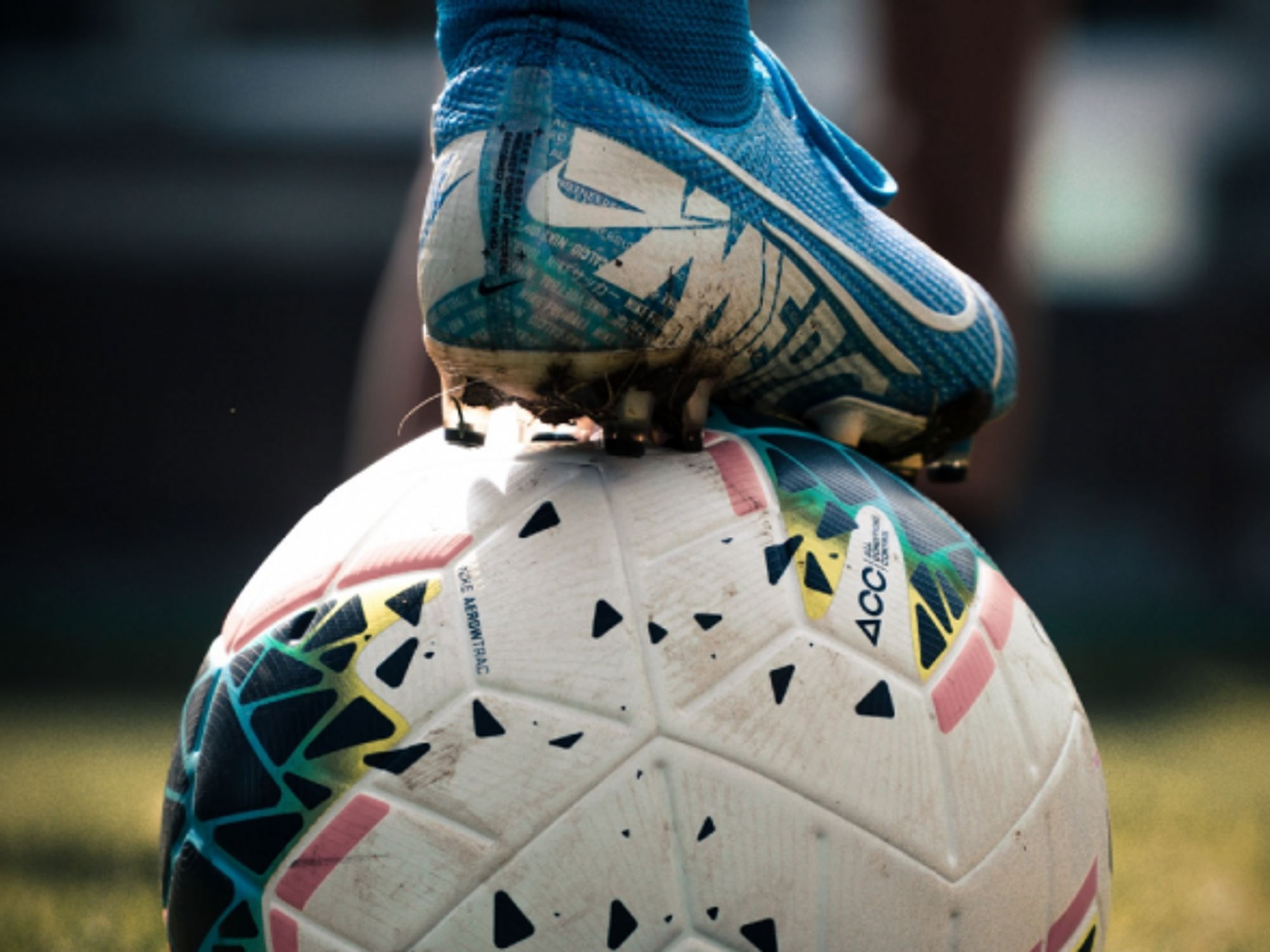 A soccer player places their foot on a soccer ball