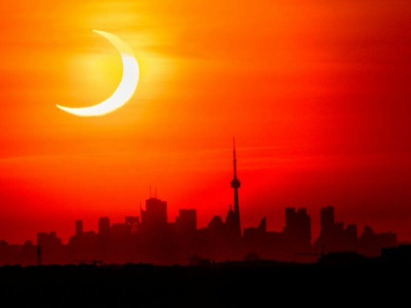 A solar eclipse shines over the skyline of Toronto, Canada