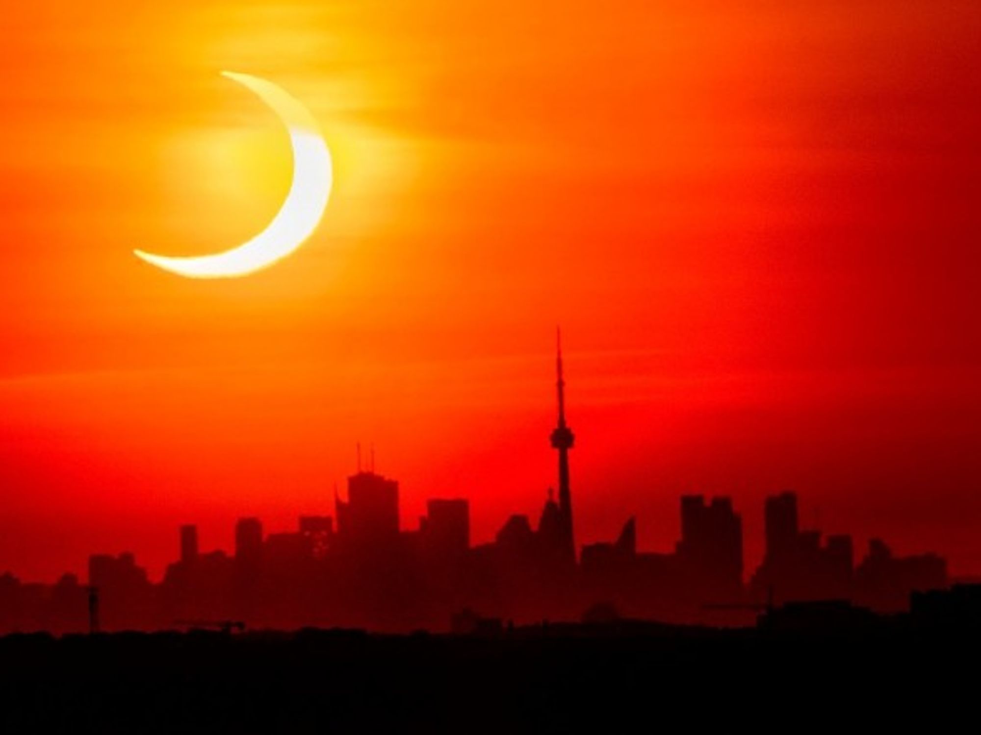 A solar eclipse shines over the skyline of Toronto, Canada