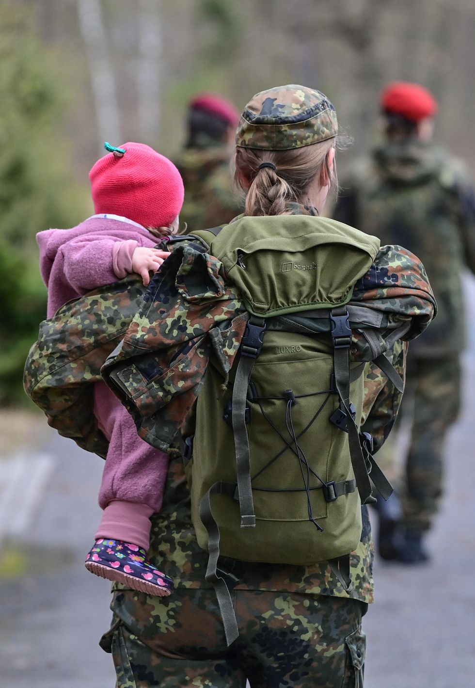 A soldier of the German Armed Forces carries a small child.