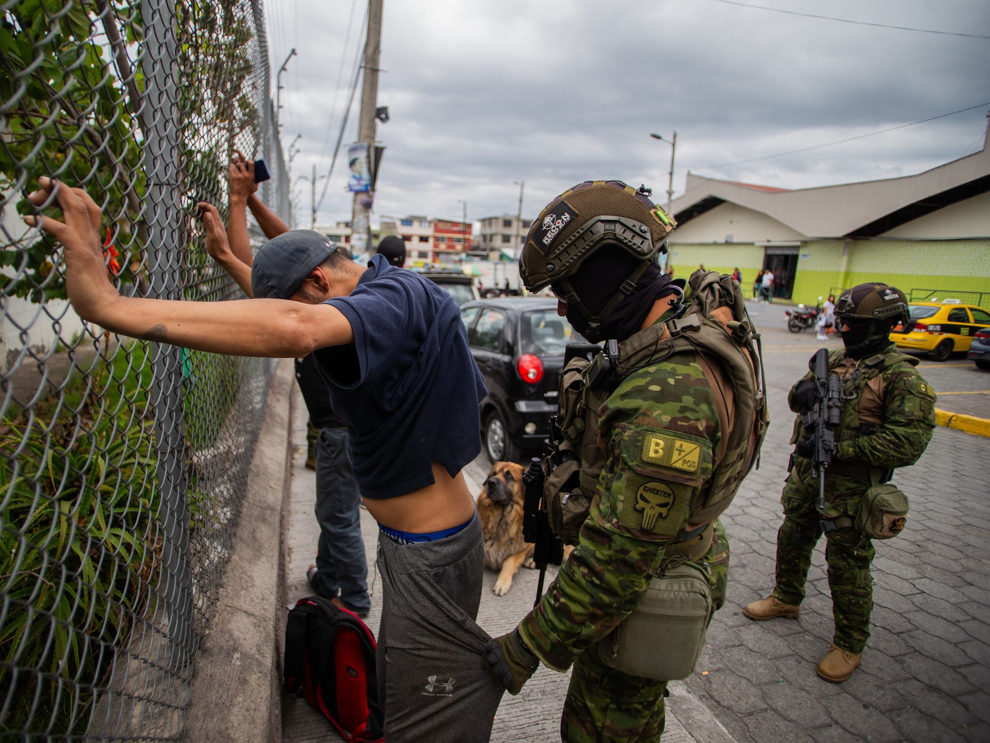 A soldier searches a man in front of the Carapungo market in Quito.
