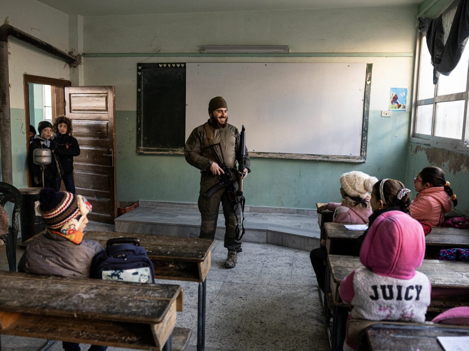 A soldier stands at the front of a classroom with young children