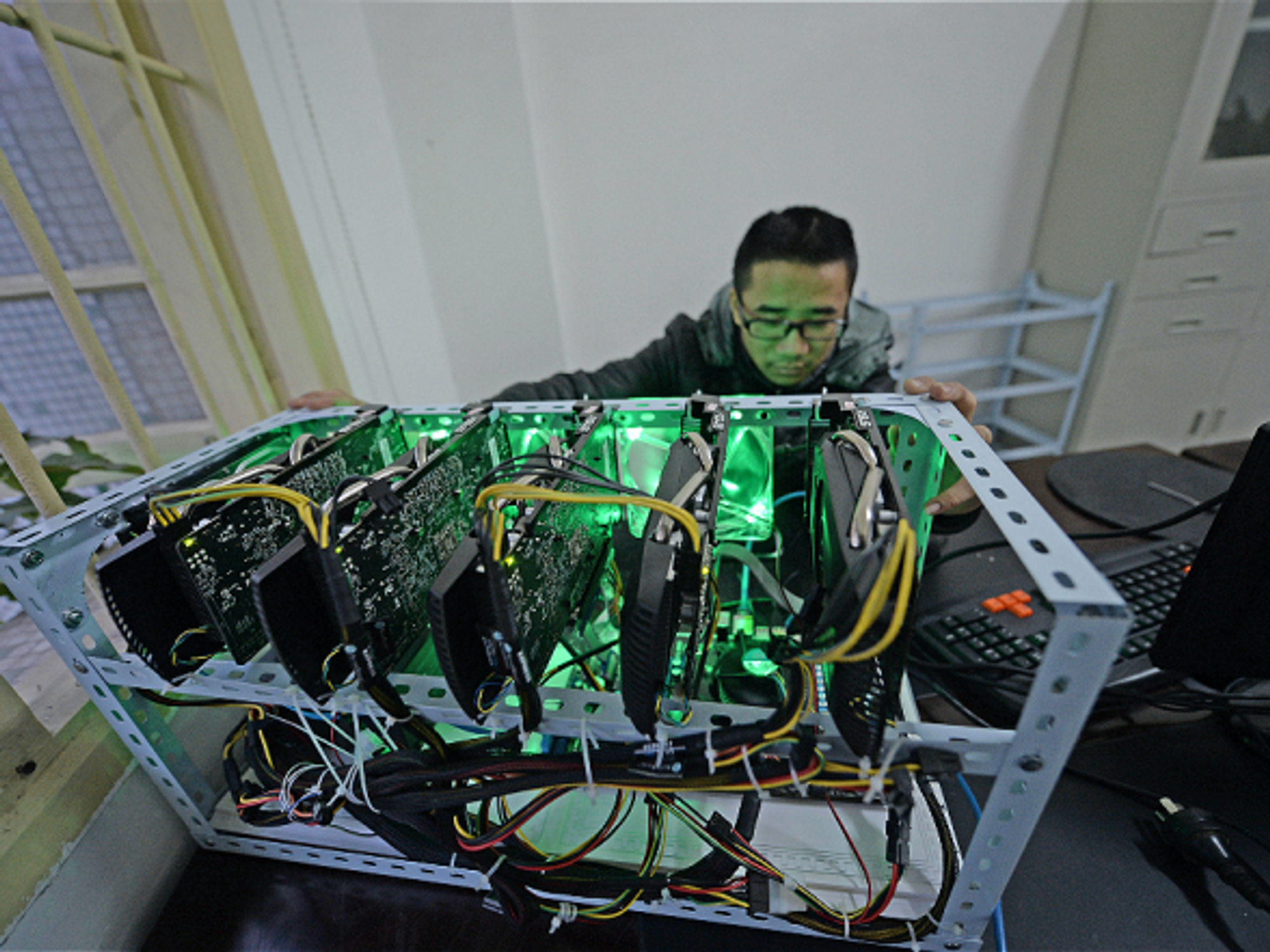 A staff monitors a 'bitcoin miner', a powerful computer with five mining cards
