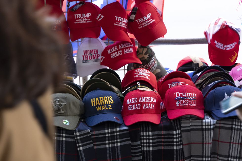 A street vendor in Manhattan's Financial District displays presidential election merchandise including hats that read 'HARRIS WALZ' 'WOMEN for TRUMP' 'TRUMP 2024 TAKE AMERICA BACK' .