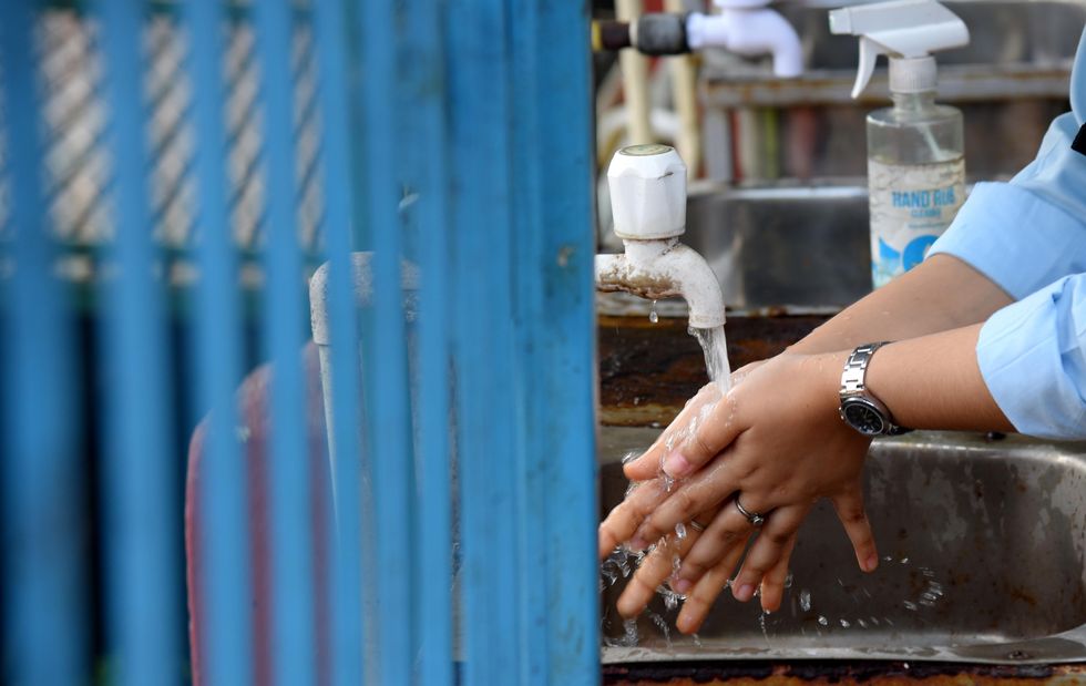 A student wash her hands before entering a class room in Guwahati, India