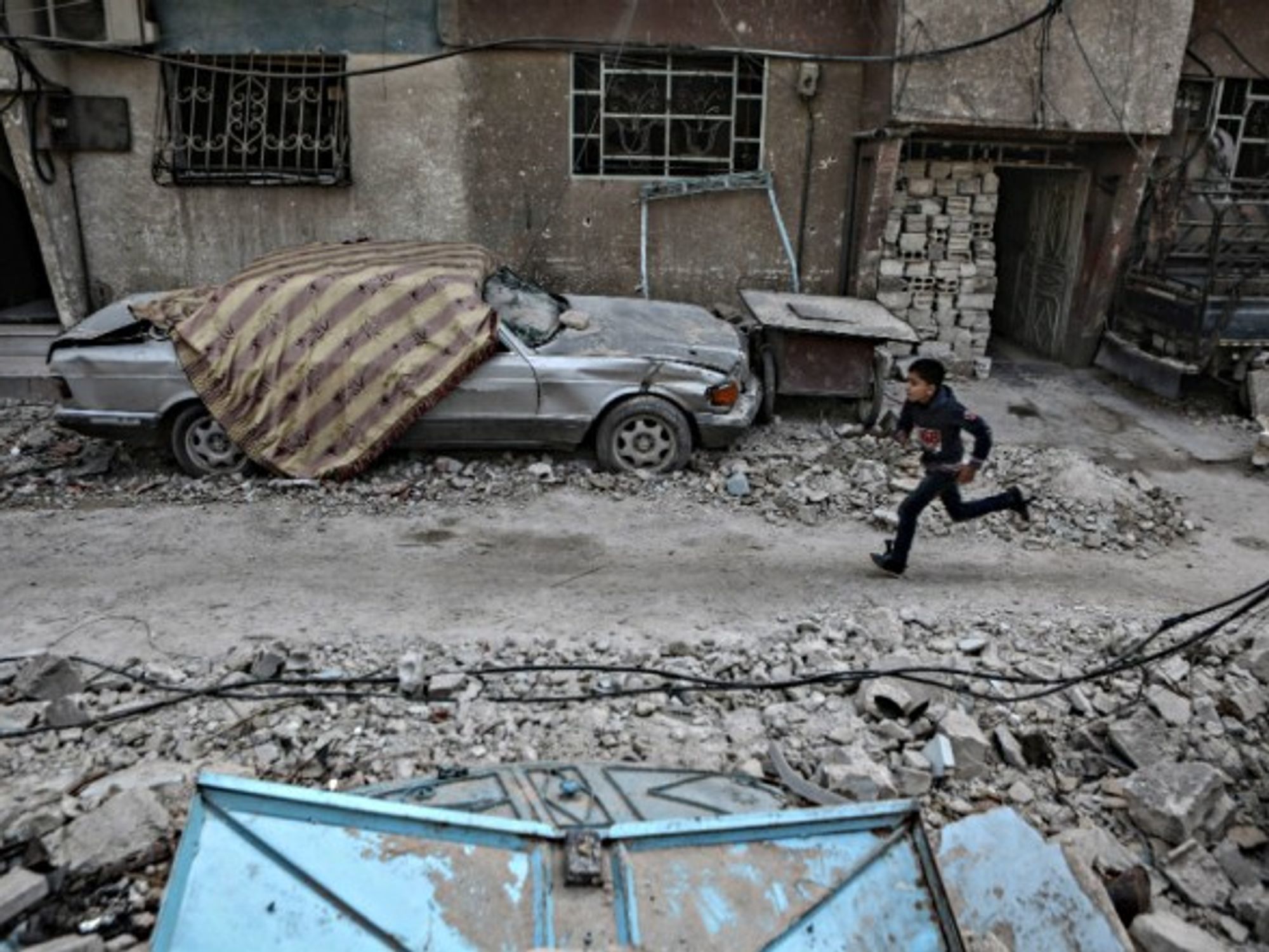 A Syrian boy runs past rubble in eastern Al Ghouta province, outside Damascus