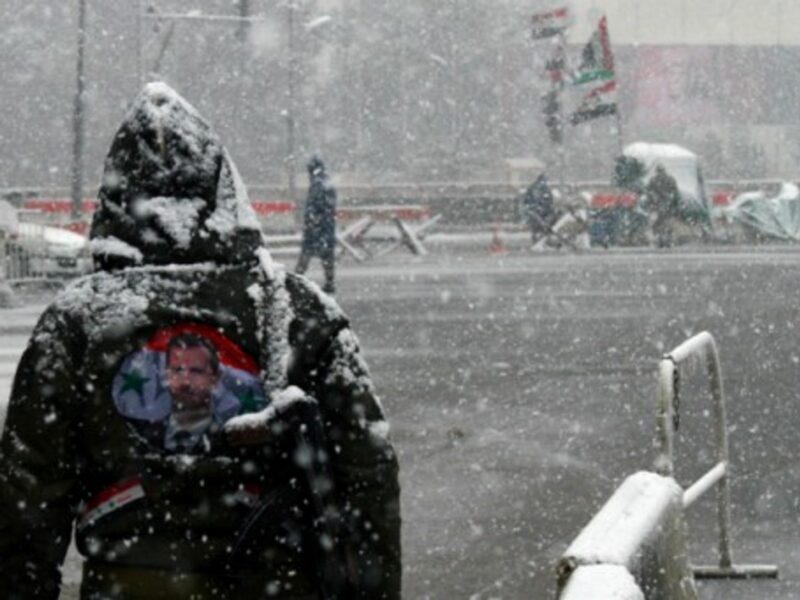 A Syrian government soldier stands in the snow in central Damascus.