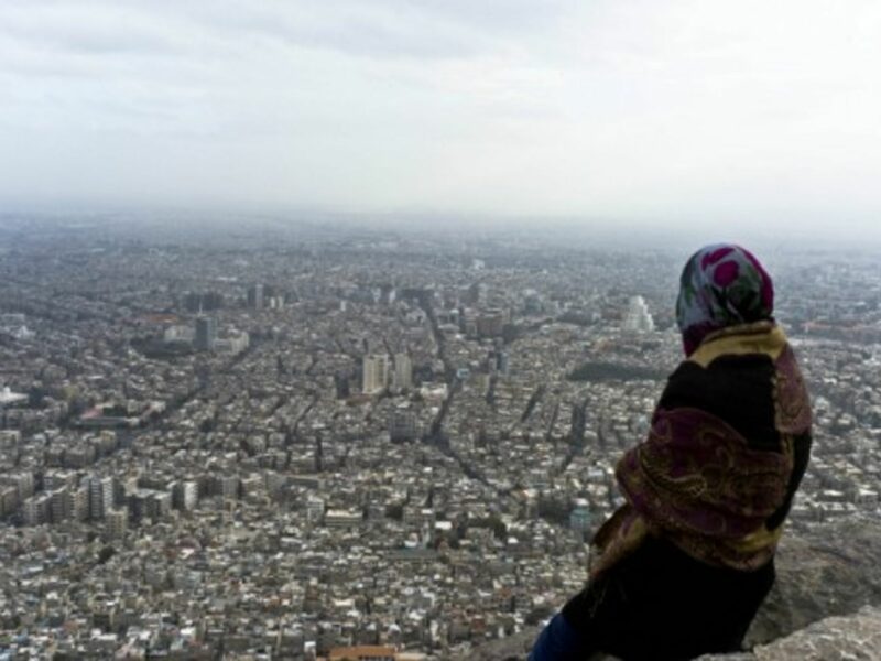 A Syrian woman looks over Damascus