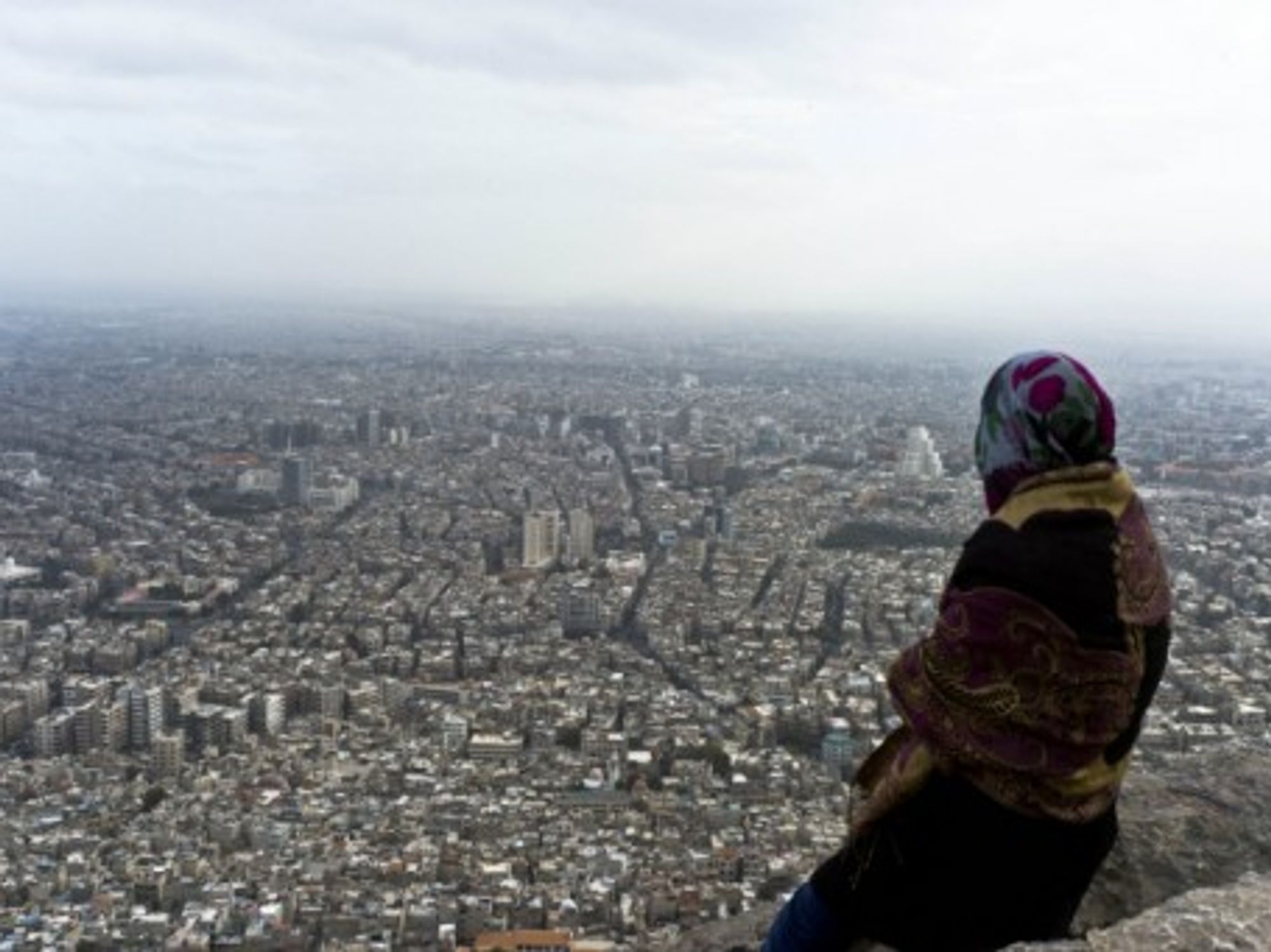 A Syrian woman looks over Damascus