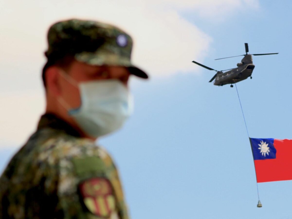 A Taiwanese soldier looks on as a helicopter rises the Taiwanese flag.