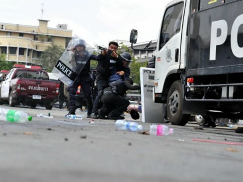 A Thai riot police officer fires on anti-government protesters in Bangkok today.
