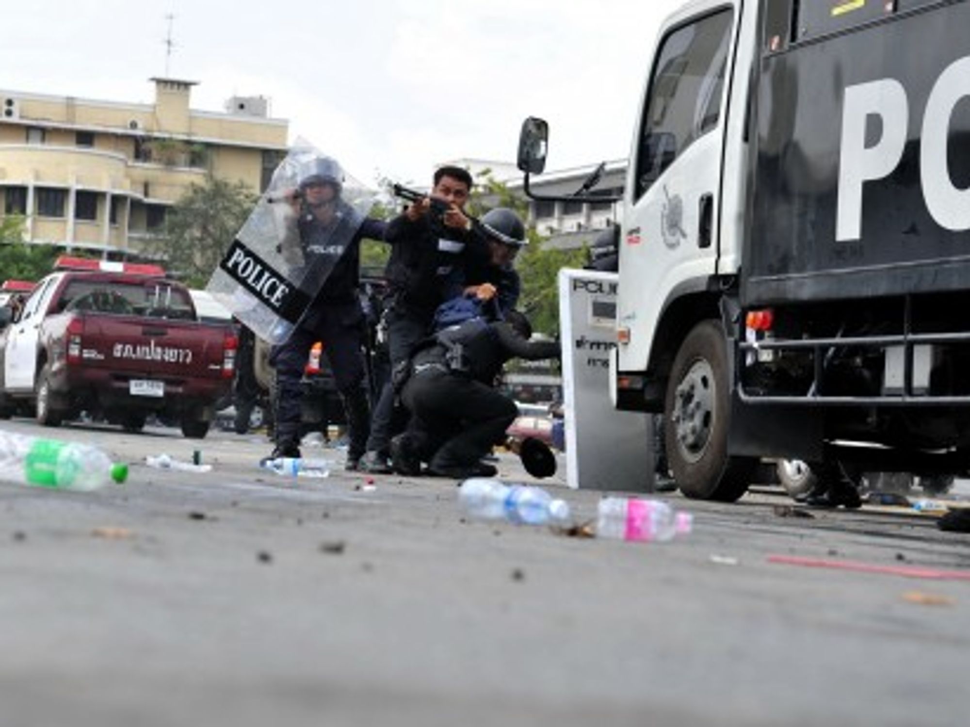 A Thai riot police officer fires on anti-government protesters in Bangkok today.