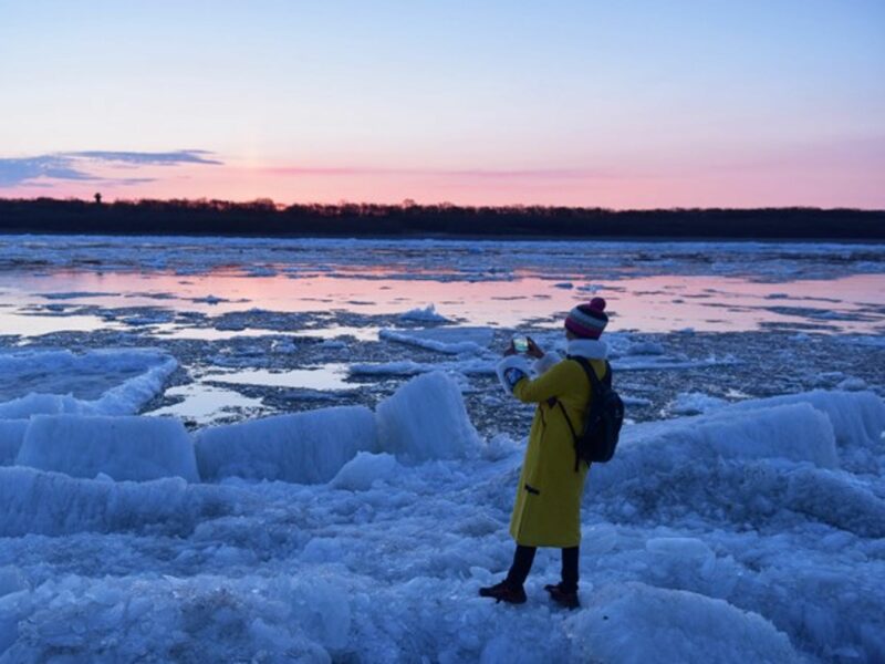A tourist takes photos of melting ice of the Heilongjiang River in northeast China in May 2019