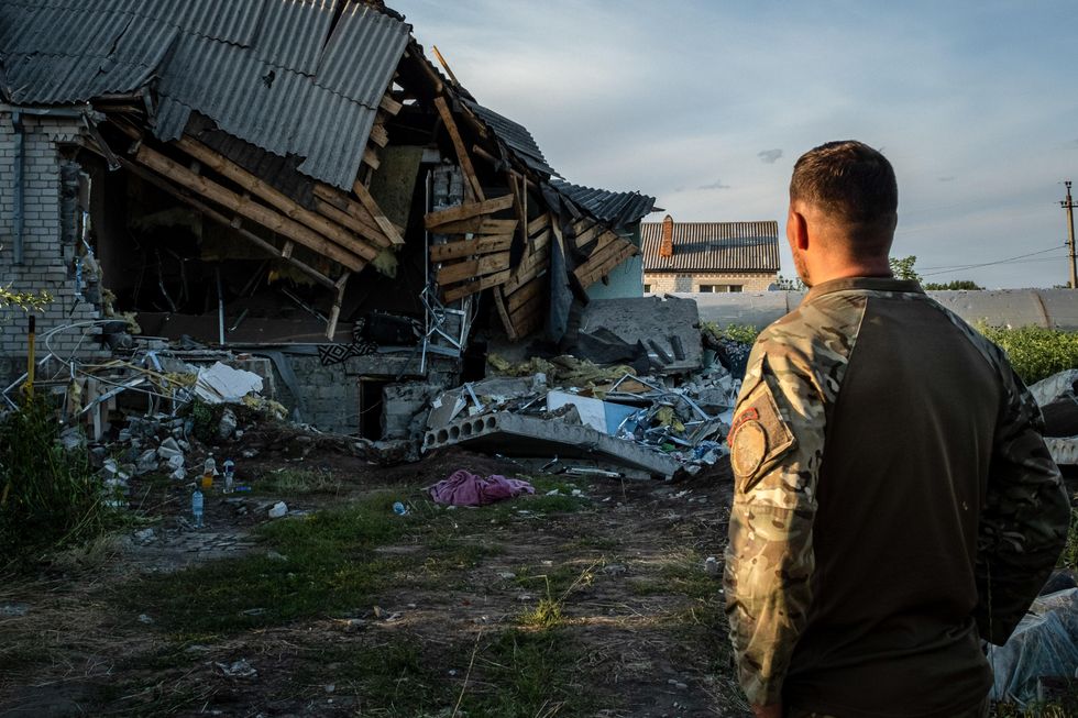 A Ukrainian soldier observes the ruins of a destroyed residential house in Slovyansk