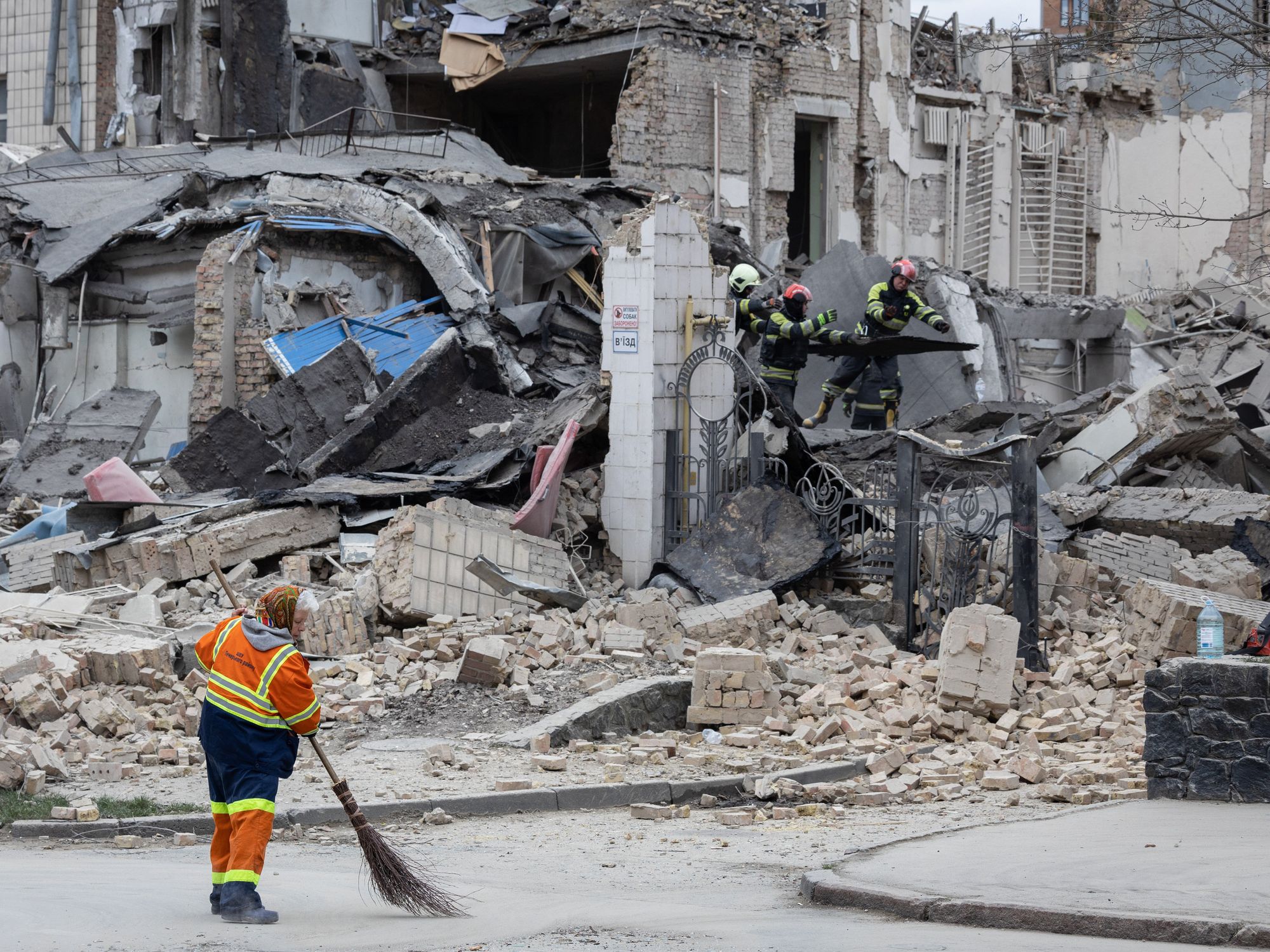 A utility worker removes rubble at the site of the building of Kyiv Academy of Art and Design.