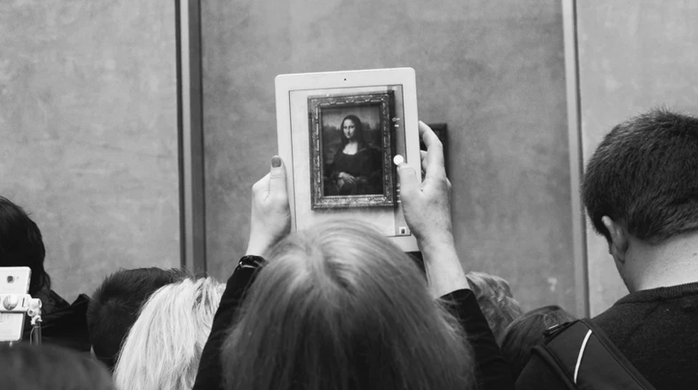 A visitor at the Louvre takes a photo of the Mona Lisa