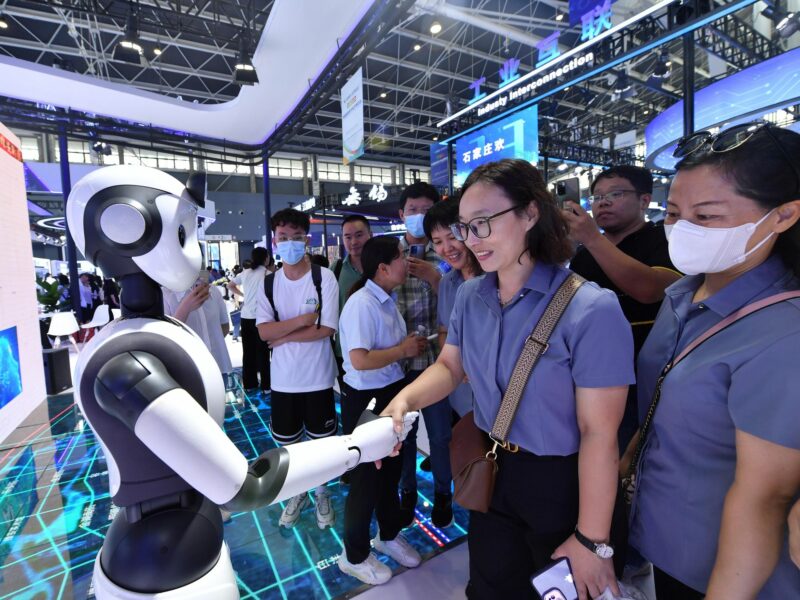 A visitor shakes hands with a humanoid robot.