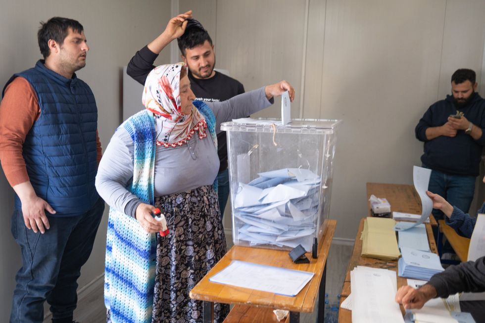 A voter casts her vote in a ballot box at a polling station during the 2024 Turkish local elections.