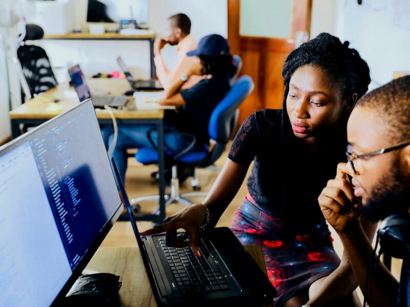 A woman and a man sitting in front of a computer.