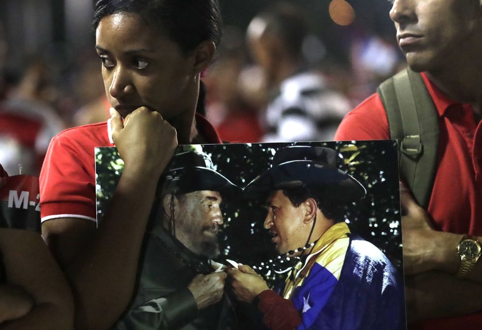 A woman carries a photo of Commander Fidel Castro and the former president of Venezuela, Hugo Chavez, in the farewell of the Cuban revolutionary.