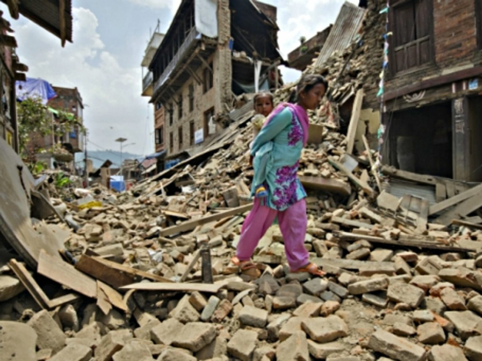 A woman carrying her baby through the debris of Kathmandu on May 16