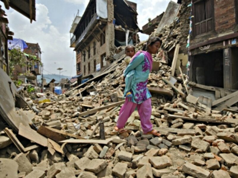 A woman carrying her baby through the debris of Kathmandu on May 16