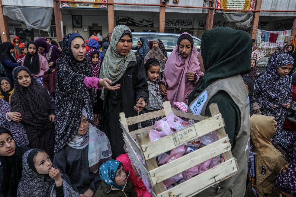 A woman distributes sweets to Muslim women after Eid al Fitr prayers at al-Quds school.