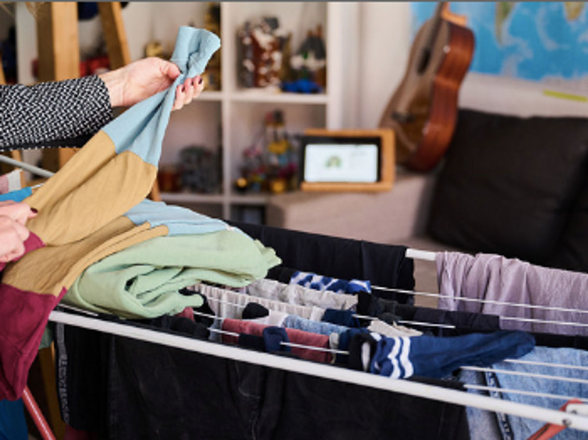 A woman folding her laundry while participating in a video conference.