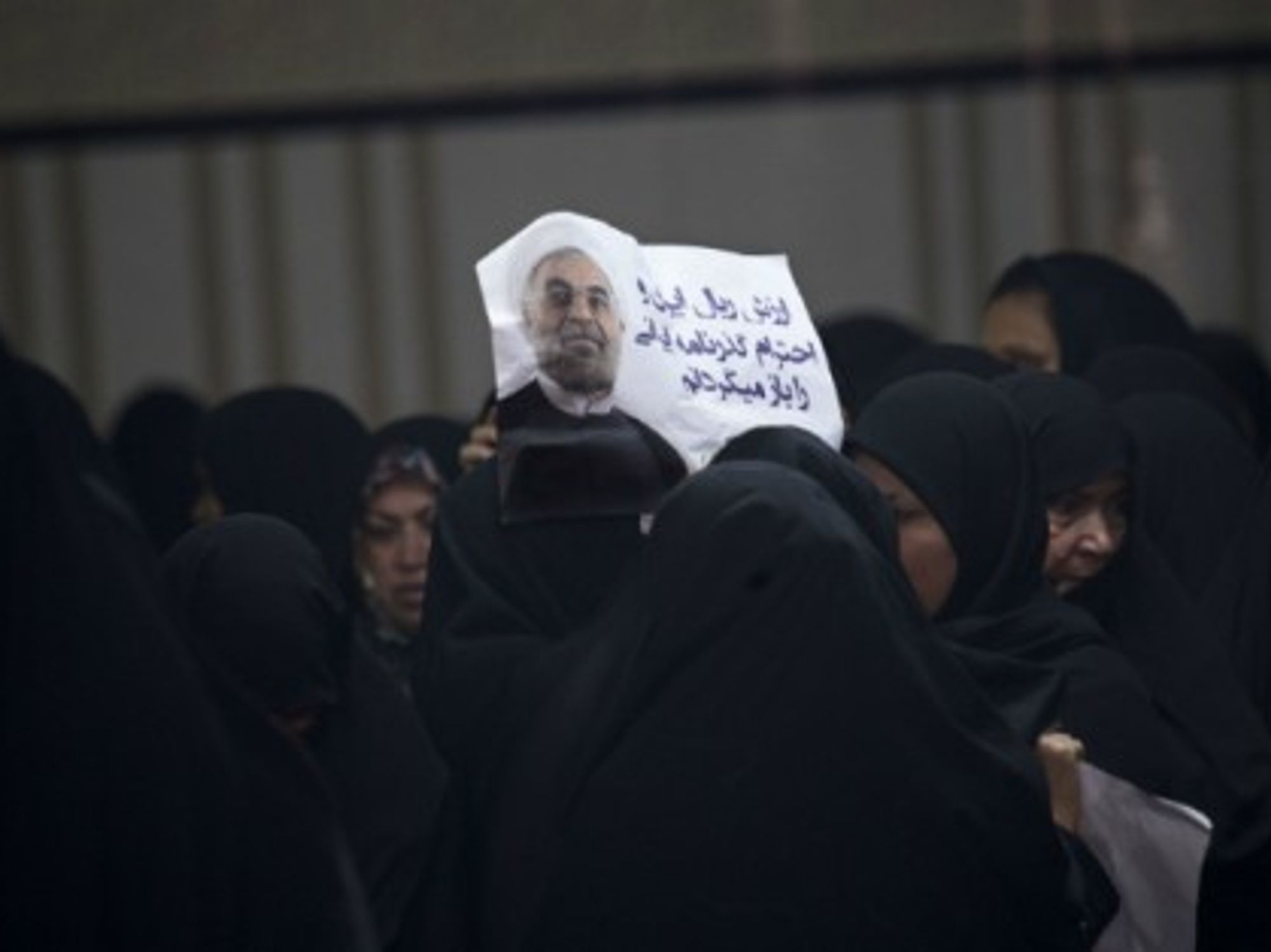 A woman helds up a poster of Iran president Hassan Rouhani