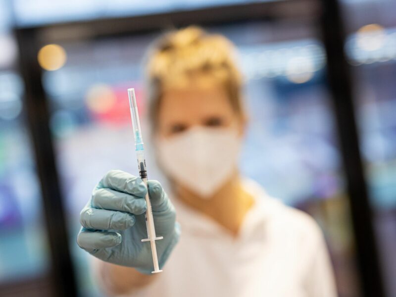 a woman holding a syringe for a COVID vaccine