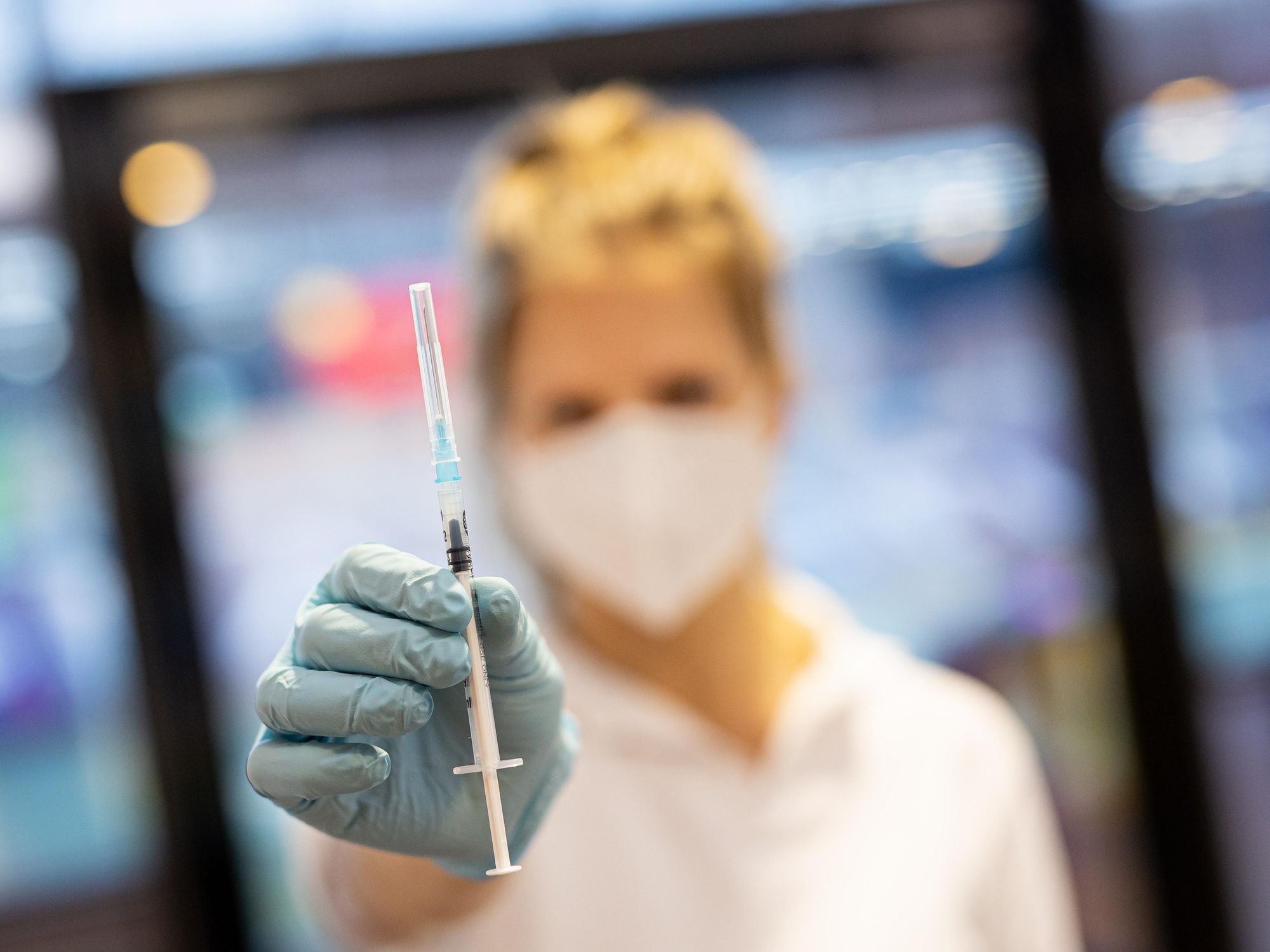 a woman holding a syringe for a COVID vaccine