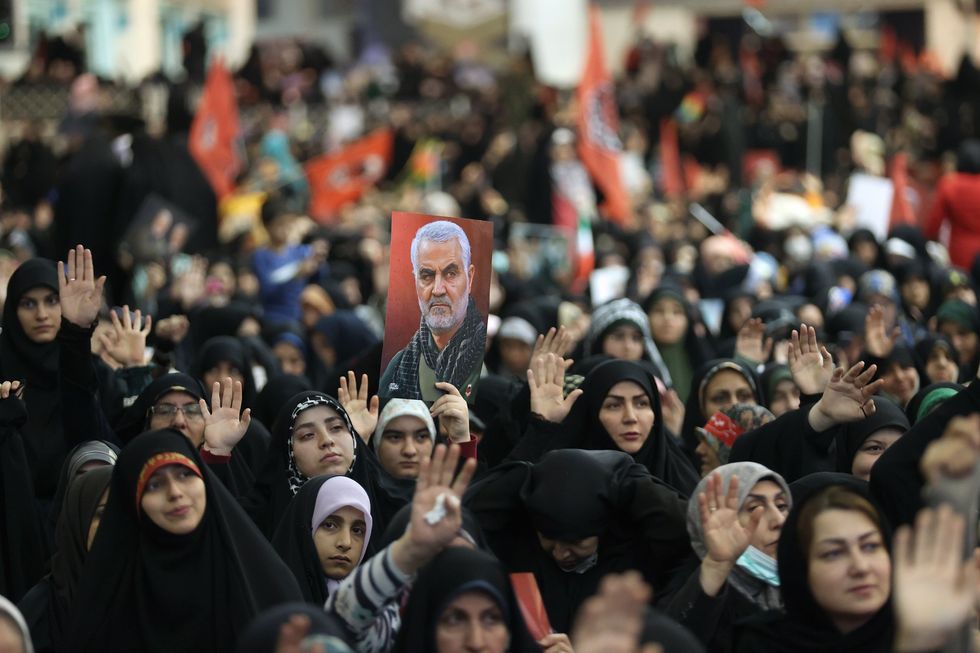 A woman holds a picture of Qasem Soleimani in a crowds, as hundreds of people gathered in Tehran on the 4th anniversary of his death.
