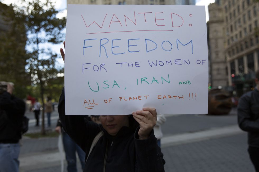 A woman holds a sign that reads ''Wanted: Freedom For the Women of USA, Iran and All Of the Planet Earth!!!''
