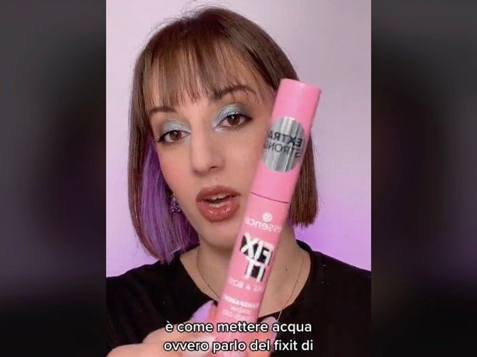 A woman holds up a makeup tube to the camera