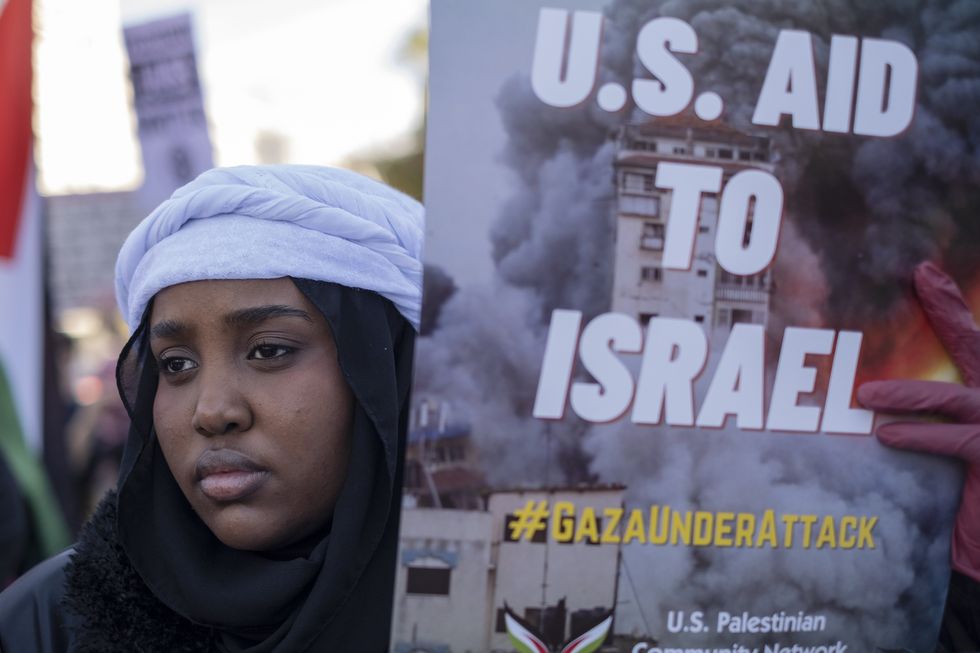 A woman holds up a sign that reads U.S. Aid To Israel #Gazaunderattack, calling for a ceasefire during a protest in Washington