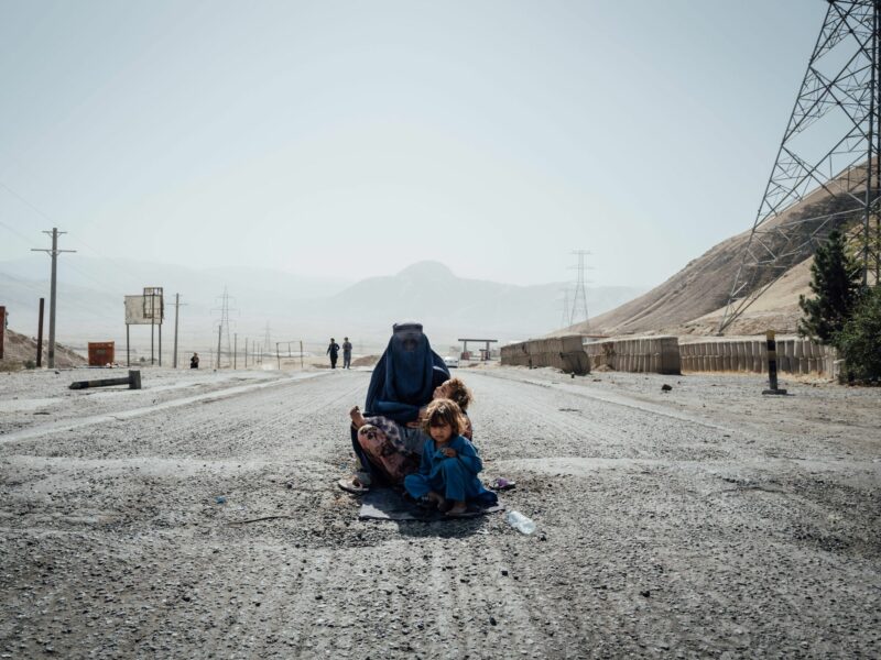 A woman in a blue burqa on the street with two small children