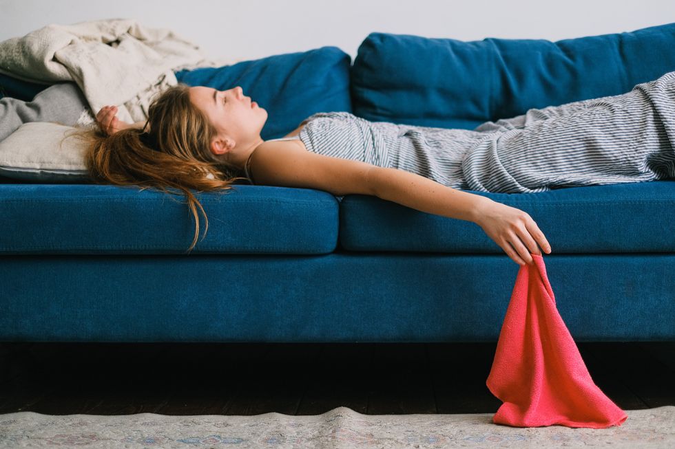A woman lies on the sofa, her hand dangling over the edge holding a cleaning cloth