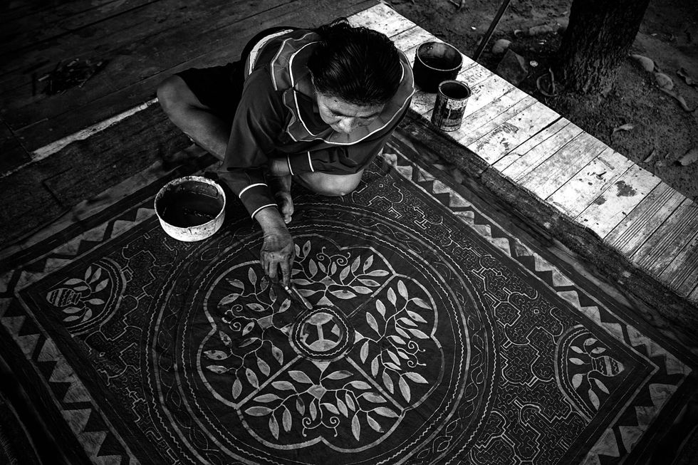 A woman painting kené.